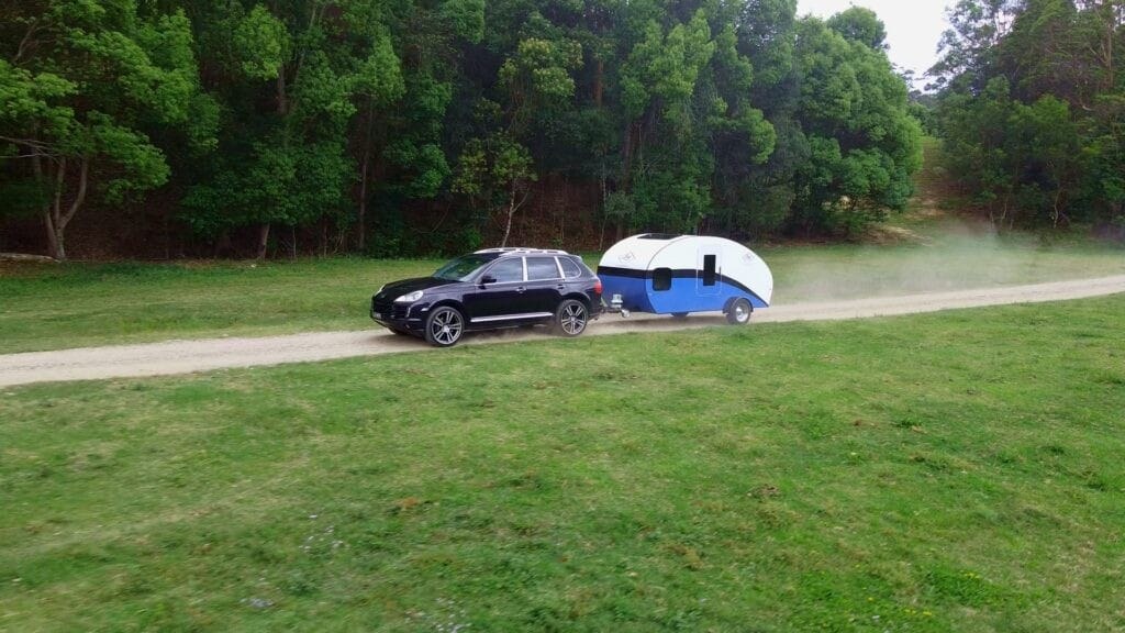 Blue JAG Teardrop Camper being towed on a dirt road, showing lightweight camper towing in Australian conditions.